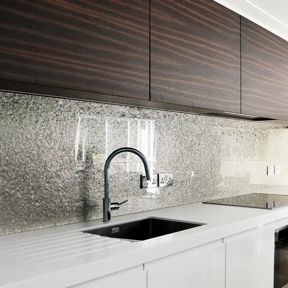 Luxury kitchen with sparkling glass splashback, sleek white countertop, and dark wood cabinets
