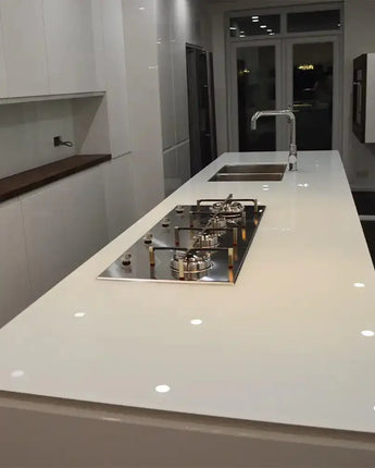 Sleek white glass kitchen island with built-in cooktop and sink, modern luxury residential design
