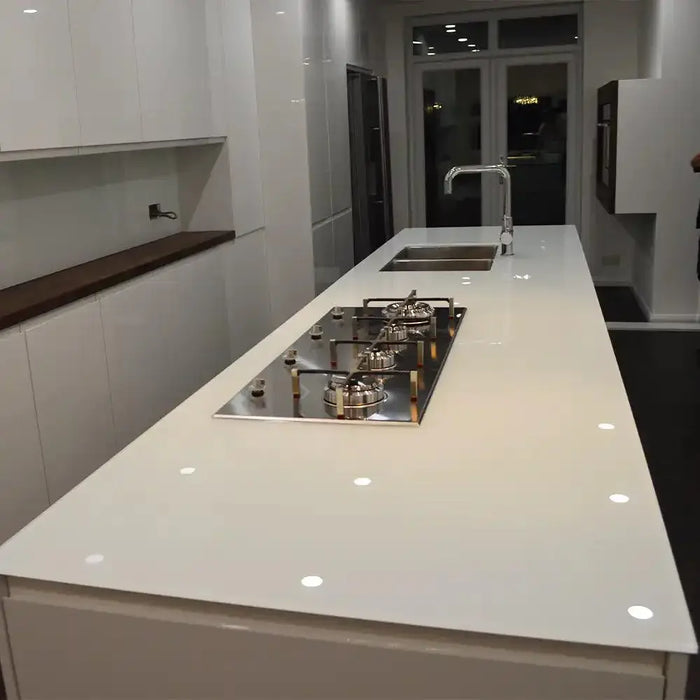 Sleek white glass kitchen island with built-in cooktop and sink, modern luxury residential design