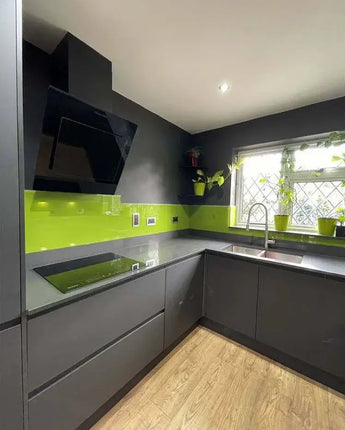 Modern kitchen with lime green glass splashback, grey cabinets, and LED-lit feature glass wall