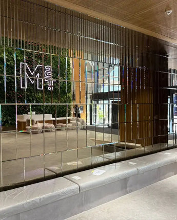 Bespoke architectural glass wall with vertical mirrored panels and LED backlighting in modern lobby