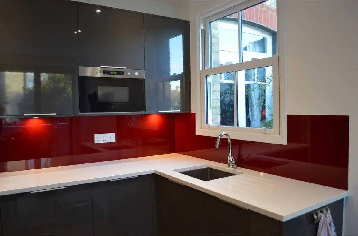 Vibrant red glass kitchen backsplash with sleek black cabinets and white countertop