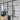 Modern interior with black framed double glass door and side panels, wooden round table, and black chairs