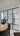 Modern interior with black framed double glass door and side panels, wooden round table, and black chairs