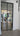 Double hinged black framed glass door leading to modern kitchen with wooden flooring and bar stools