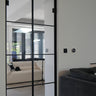 Modern double hinged glass door with black frame in a bright living room interior