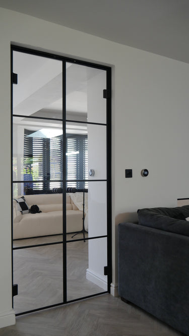 Modern double hinged glass door with black frame in a bright living room interior