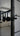 Close-up of modern black metal double hinged glass door with black knobs in a stylish living room