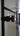 Close-up of modern black metal door handle on glass double hinged door with frame in bright room