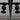 Close-up of black double hinged door handles on glass doors with light patterned floor background
