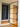 Modern hinged glass door with black metal frame in hallway with black wall-mounted storage panels