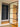Modern hinged glass door with black metal frame in hallway with black wall-mounted storage panels