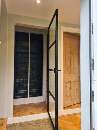 Modern interior with a black metal framed glass hinged door and wooden floor