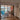 Modern living room with black framed glass double doors opening to dining area featuring wooden floors