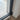 Close-up of black metal frame double hinged glass door on wood floor with white wall baseboard