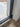 Close-up of black metal frame double hinged glass door on wood floor with white wall baseboard