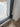 Close-up of black metal frame double hinged glass door on wood floor with white wall baseboard