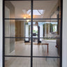 modern black double hinged steel framed glass door in bright spacious interior with wood flooring