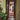 Glass hinged door with black frame in hallway decorated with patterned rug and Christmas tree