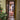 Glass hinged door with black frame in hallway decorated with patterned rug and Christmas tree