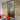 Modern interior with black-framed glass hinged door, exposed brick wall, and bright orange sofa