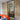 Modern interior with black-framed glass hinged door, exposed brick wall, and bright orange sofa