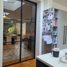 Black double hinged glass door with frame leading to a living space, adjacent to refrigerator with photos and notes