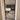 Modern black framed glass hinged door with white trim showing view into living room with beige sofa and wooden flooring
