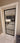 Modern black framed glass hinged door with white trim showing view into living room with beige sofa and wooden flooring