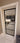 Modern black framed glass hinged door with white trim showing view into living room with beige sofa and wooden flooring