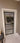 Modern hinged glass door with black metal frame and white trim in beige interior
