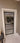 Modern hinged glass door with black metal frame and white trim in beige interior
