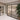 Modern double-hinged black framed glass doors in elegant beige room with large potted plant
