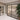 Modern double-hinged black framed glass doors in elegant beige room with large potted plant