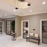 Modern interior hallway with glass hinged doors framed in black metal and tiled floor