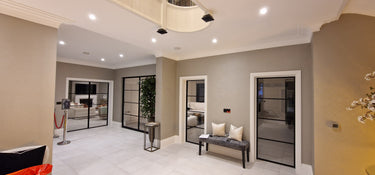Modern interior hallway with glass hinged doors framed in black metal and tiled floor