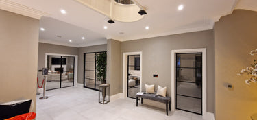 Modern interior hallway with glass hinged doors framed in black metal and tiled floor