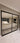 Modern double hinged black metal frame glass door separating tiled hallway and living room