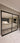 Modern double hinged black metal frame glass door separating tiled hallway and living room
