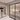 Modern interior with black framed double hinged glass doors separating two living rooms with beige sofas