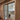 Double hinged glass doors with metal frame separating hallway with patterned rug from modern living room