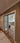Double hinged glass doors with metal frame separating hallway with patterned rug from modern living room