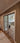 Double hinged glass doors with metal frame separating hallway with patterned rug from modern living room