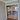 Double hinged glass doors with gold frames and handles in modern interior with wooden herringbone floor