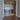 Double hinged glass doors with gold frame and handles leading to a living room with sea view