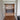 Double hinged glass doors with brass frames opening to a modern room with dark cabinet and lamps
