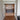Double hinged glass doors with brass frames opening to a modern room with dark cabinet and lamps