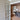 Interior view of a double hinged glass door with bronze frame opening into a room with herringbone wood flooring and modern decor