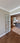Interior view of a double hinged glass door with bronze frame opening into a room with herringbone wood flooring and modern decor
