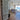 Modern double hinged glass door with metal frame opening to living room with sofa and ocean view